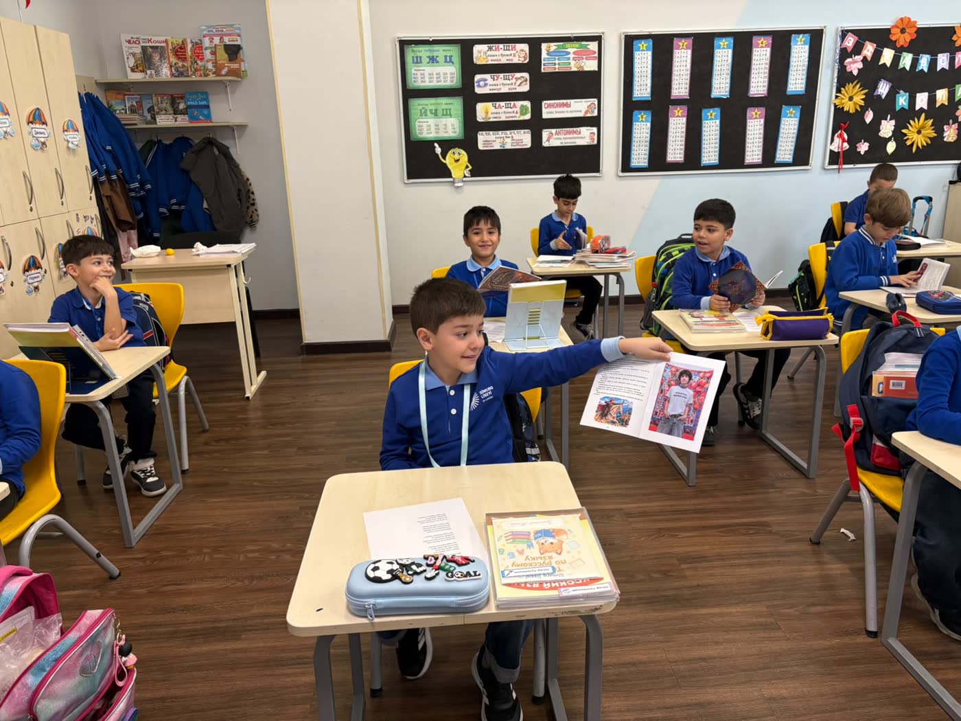 A boy at his desk holds the book open at the last page, which shows a photo of Jamal in a slogan T-shirt.